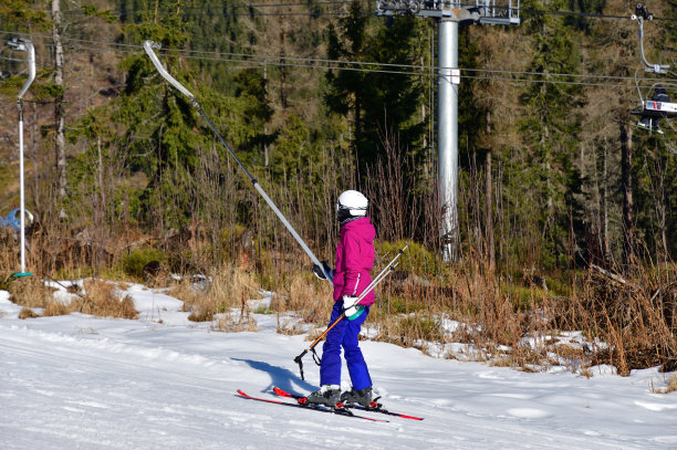在多雪的冬天，这个女孩在滑雪缆车上拉着一根缆绳图片下载