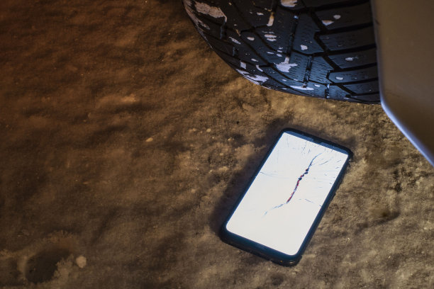 智能手机的屏幕在夜间移动汽车轮胎时会开裂，前后背景因散景效果而模糊图片下载