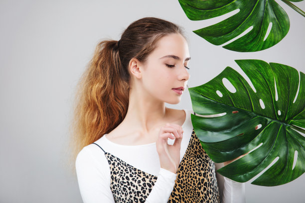 年轻美丽的女孩模型与热带树叶肖像在白色的背景在工作室图片下载