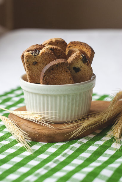 白碗里装葡萄干饼干，干耳朵，绿色纺织品图片下载