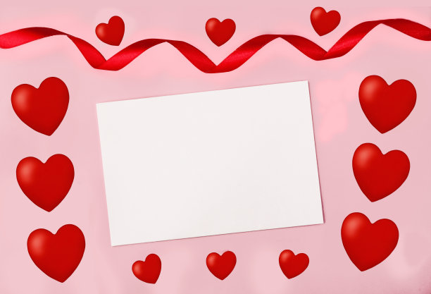 白色笔记本纸在粉红色的背景附近红色的心和缎带。情人节的概念，爱，情人，爱的祝愿。本空间图片下载