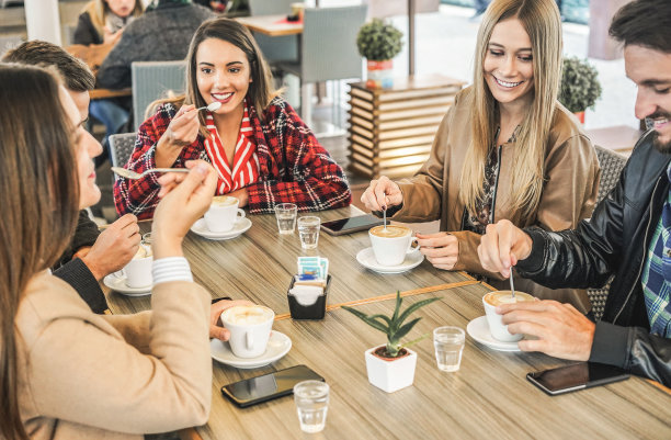 年轻的朋友喝着牛奶咖啡，在酒吧面包店做早餐-快乐的人们在冬天喝着卡布奇诺-友谊和食物概念-关注正确的女孩的脸图片下载