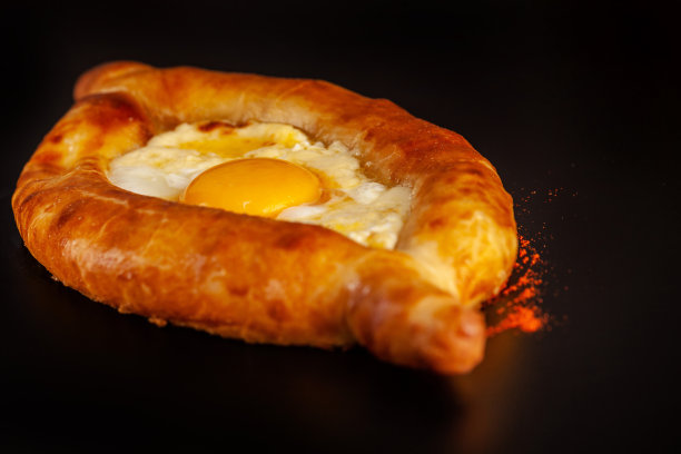 传统的格鲁吉亚和亚美尼亚美食。哈切布里，苏鲁古尼奶酪和蛋黄在黑色的背景上。的背景图片。复制空间，选择焦点图片下载