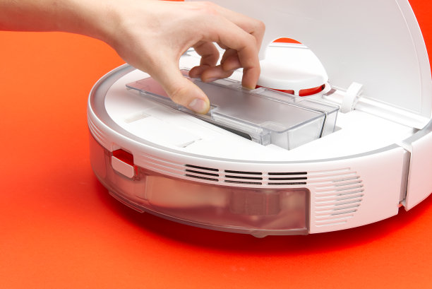 机器人真空吸尘器，清洁垃圾桶和清洁过滤器。机器人真空吸尘器隔离在红色背景。图片下载