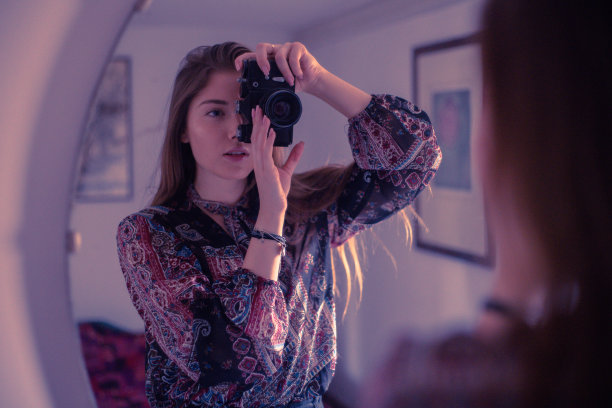 小女孩拿着相机站在镜子前自拍图片下载