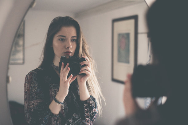 小女孩拿着相机站在镜子前自拍图片下载