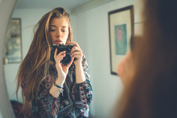 小女孩拿着相机站在镜子前自拍图片下载