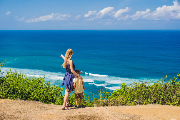 妈妈和儿子在海滩上的悬崖上旅行。空荡荡的天堂海滩，印度尼西亚巴厘岛的蓝色海浪。Suluban和Nyang Nyang的地方。和孩子一起旅行的概念图片下载