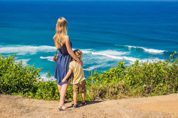 妈妈和儿子在海滩上的悬崖上旅行。空荡荡的天堂海滩，印度尼西亚巴厘岛的蓝色海浪。Suluban和Nyang Nyang的地方。和孩子一起旅行的概念图片下载
