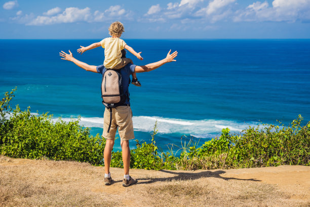 爸爸和儿子在海滩上的悬崖上旅行。空荡荡的天堂海滩，印度尼西亚巴厘岛的蓝色海浪。Suluban和Nyang Nyang的地方。和孩子一起旅行的概念图片下载