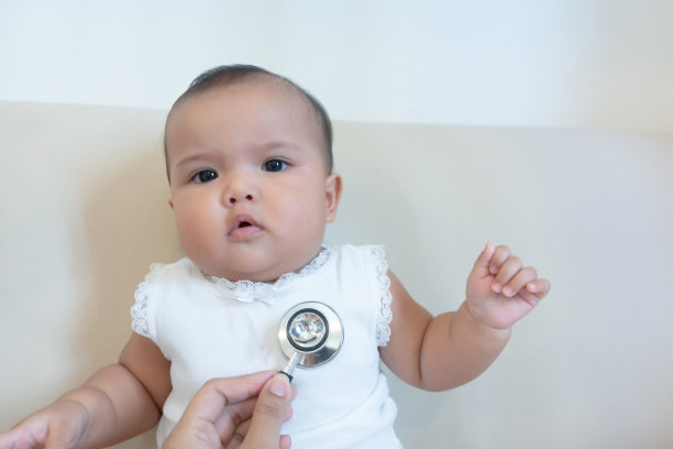 新生儿在沙发上接受医生的听诊器检查图片下载