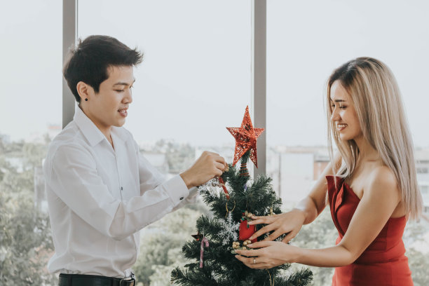 年轻的亚洲夫妇在家里一起装饰圣诞树，节日的概念。图片下载