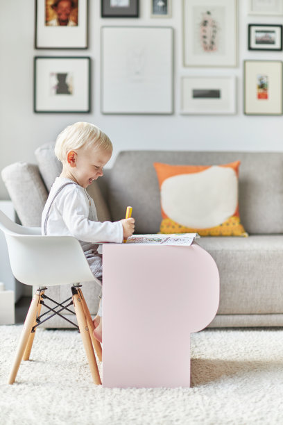 一个蹒跚学步的孩子坐在一张小桌子旁画画。图片下载