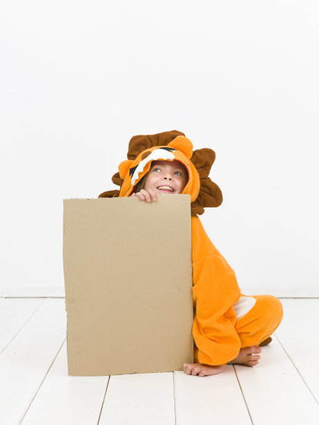 漂亮的金发女孩穿着舒适的狮子服装，在白色的墙壁前举着一个棕色的标志图片下载