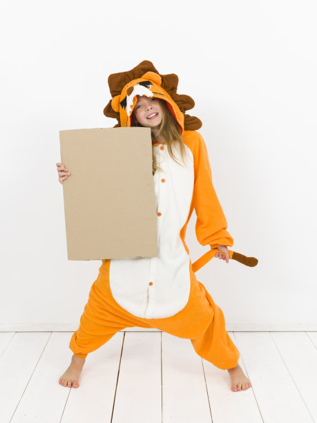 漂亮的金发女孩穿着舒适的狮子服装，在白色的墙壁前举着一个棕色的标志图片下载