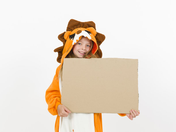 漂亮的金发女孩穿着舒适的狮子服装，在白色的墙壁前举着一个棕色的标志图片下载