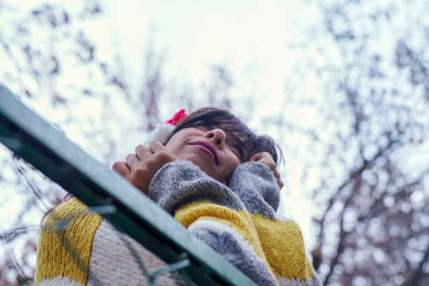 一个女人躲在铁丝网后面。美丽的绿眼睛女子在秋日听音乐图片下载