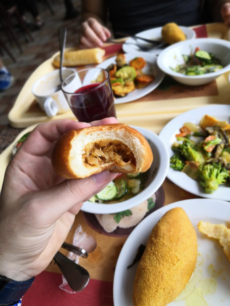 一名男子拿着一块被咬过的包着卷心菜的传统乌克兰面包图片下载