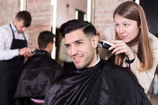 理发师用电动理发器为顾客设计发型图片下载