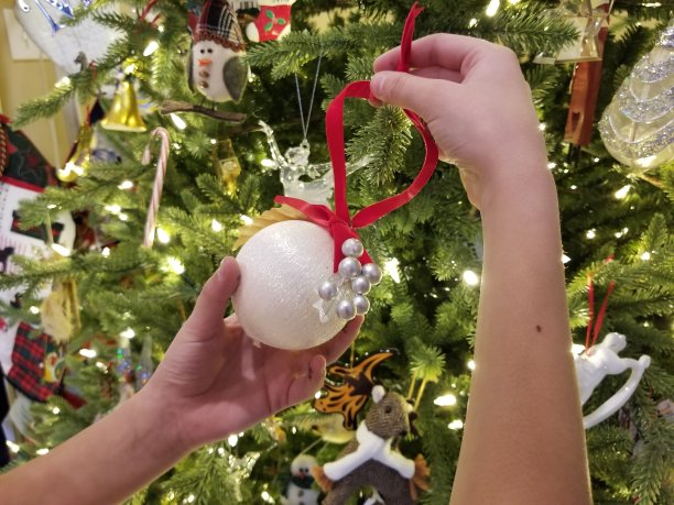 孩子的手在圣诞树上挂装饰品图片下载