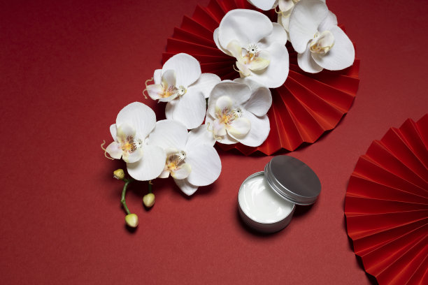 以中国红色为背景，以纸制艺术和亚洲花卉为背景，拍摄白皙的护肤照片图片下载