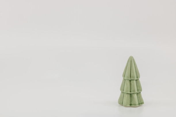 绿色的圣诞树在陶瓷手工制作的陶瓷为圣诞节装饰和节日派对在白色的背景图片下载