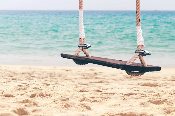 热带岛屿的沙滩和海洋上的木制秋千图片下载