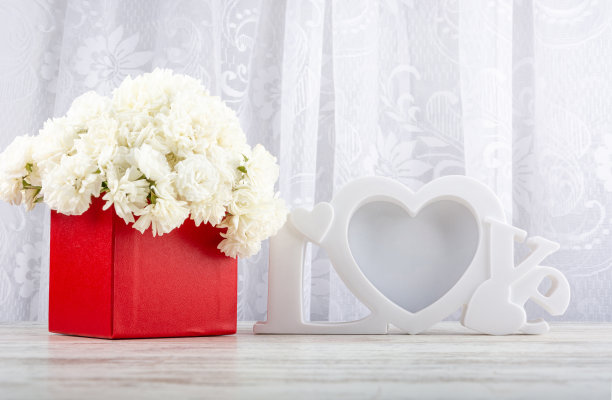 一束白玫瑰在一个红色的盒子和一个白色的相框特写。图片下载