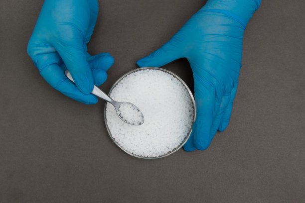 塑料颗粒。聚丙烯，聚乙烯球在手与手套。生产过程中实验室塑料的质量控制图片下载