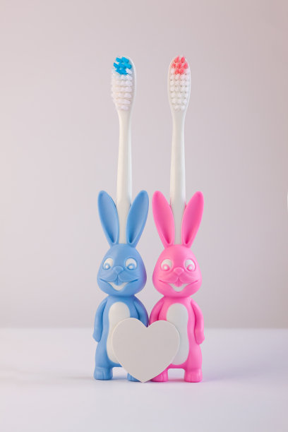 儿童的牙刷以可爱的兔子的形式在白色的背景上孤立。两只兔子有着空白的心。图片下载