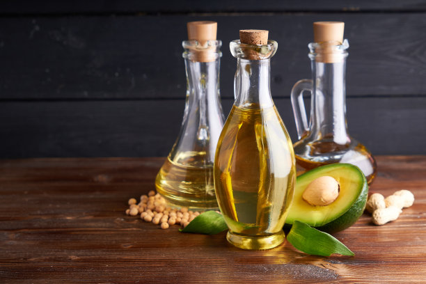 玻璃瓶里的健康植物油。鳄梨油，鹰嘴豆油，花生油，杏仁油。暗的背景图片下载