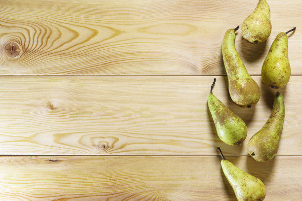 纹理分明的黄色木桌上放着各种熟多汁的梨图片下载