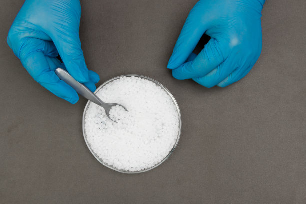 塑料颗粒。聚丙烯，聚乙烯球在手与手套。生产过程中实验室塑料的质量控制图片下载