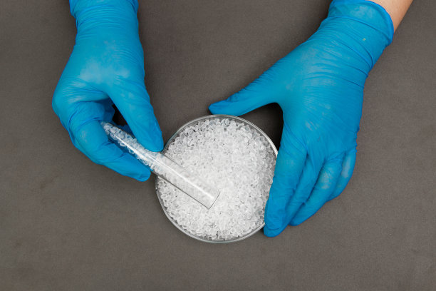 塑料颗粒。聚乙烯颗粒和手与手套。生产过程中实验室塑料的质量控制。双酚a是免费的。图片下载