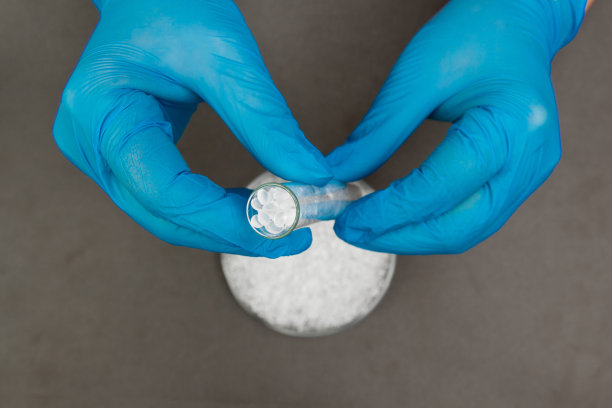 塑料颗粒。聚乙烯颗粒和手与手套。生产过程中实验室塑料的质量控制。双酚a是免费的。图片下载