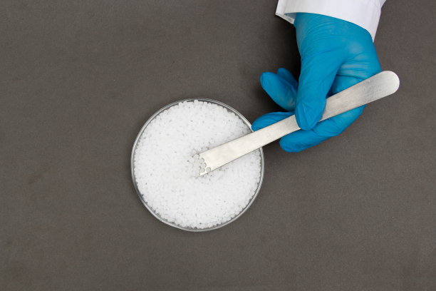 塑料颗粒。聚丙烯，聚乙烯球在手与手套。生产过程中实验室塑料的质量控制图片下载