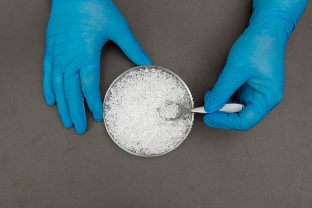 塑料颗粒。聚乙烯颗粒和手与手套。生产过程中实验室塑料的质量控制。双酚a是免费的。图片下载