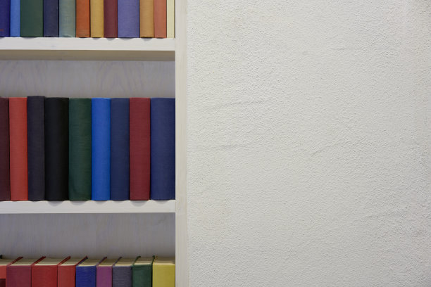 书架上有彩色的书，白色的灰泥墙，复印空间图片下载