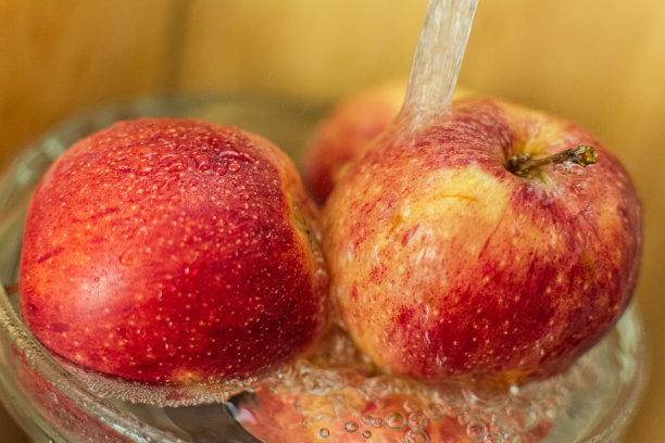 鲜红漂亮多汁熟透的苹果在流水下，讲究卫生，洗水果图片下载