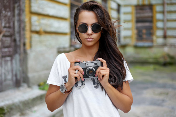 街头时尚肖像的漂亮女人戴着太阳镜与照片相机图片下载