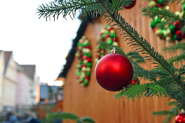 在传统的德国圣诞市场上，闪亮的红色圣诞树装饰品与销售摊位在模糊的背景图片下载