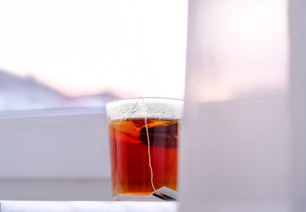 白色窗台上放着一杯透明的红茶，背景是天空。早....早餐。图片下载