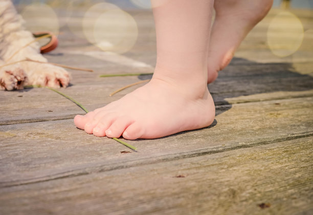 孩子光着脚站在木制露台上图片下载