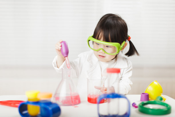 蹒跚学步的女孩在白色背景下扮演科学家的角色图片下载