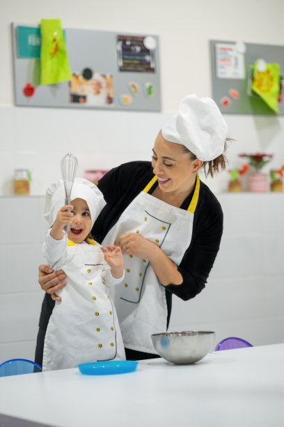 年轻的母亲正在和她的女儿一起做饭图片下载