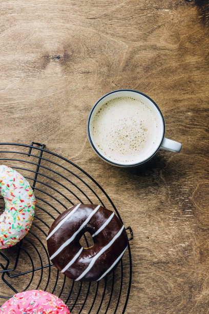 多彩的甜甜圈早餐组成与不同的颜色风格的甜甜圈和新鲜的咖啡在木制的背景。前视图。平躺图片下载