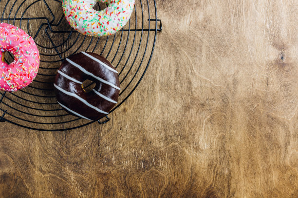 多彩的甜甜圈早餐组成与不同的颜色风格的甜甜圈和新鲜的咖啡在木制的背景。前视图。平躺图片下载