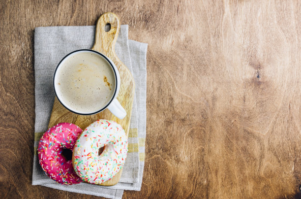 多彩的甜甜圈早餐组成与不同的颜色风格的甜甜圈和新鲜的咖啡在木制的背景。前视图。平躺图片下载