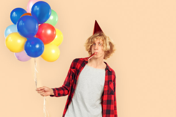 年轻人拿着氦气球，吹着派对号角图片下载