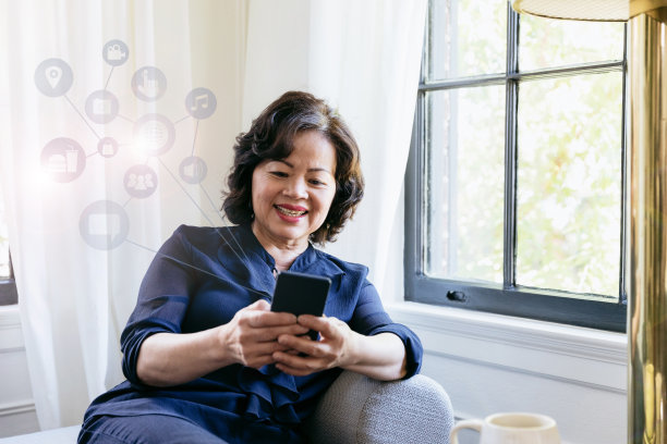 一位年长女性在家放松时使用智能手机图片下载